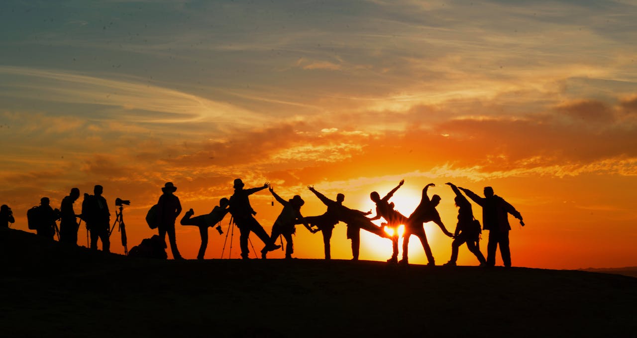 services-01 Group of people silhouetted against a vibrant sunset, showcasing unity and joy.