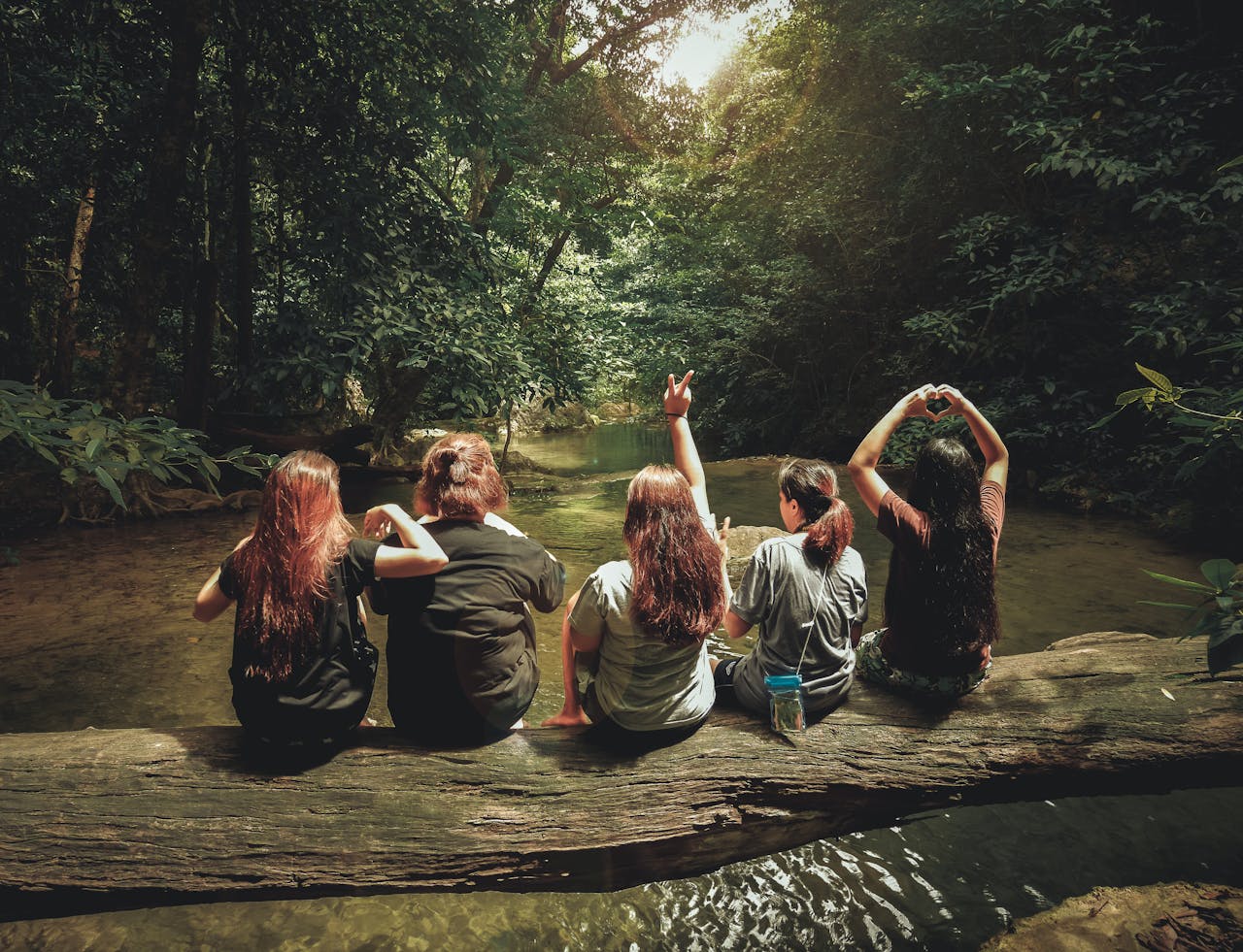 about-06 Five women enjoying nature on a log by a river in the forest, Tambon Ban Tai, Thailand.