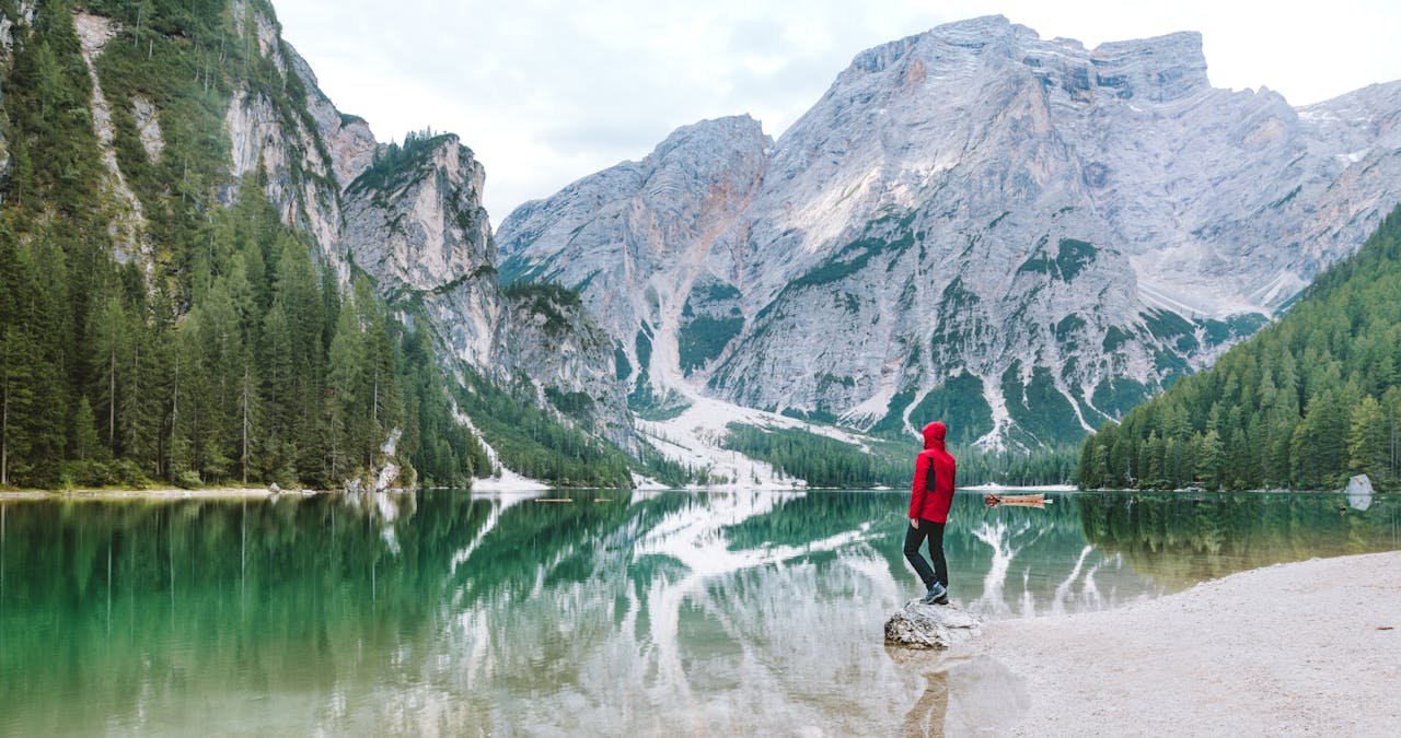 about-02 Person standing by the scenic Lake Braies with majestic Dolomite mountains reflected in the water.